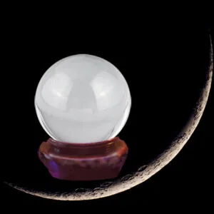 Clear crystal ball mounted on a dark red wooden stand against black background