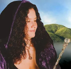 Woman with long curly hair wearing purple hooded cloak holds wooden wand near coastal cliff