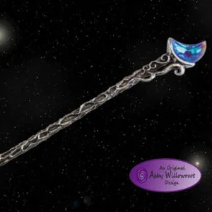Decorative wand with silver chain handle and blue iridescent moon-shaped crystal top against starry night sky
