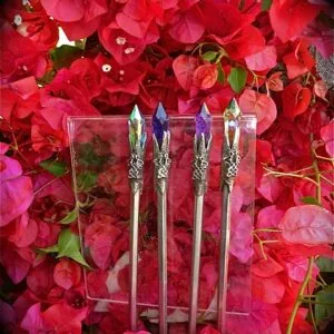 Four decorative wands with ornate handles displayed against red and pink bougainvillea flowers