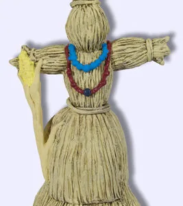 Straw figure with outstretched arms, blue necklace, and red mouth detail tied at waist and skirt