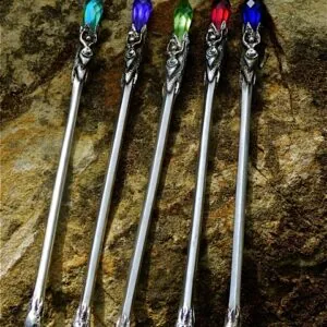 Five silver wands with ornate handles topped with colored gemstones in turquoise, blue, green, red, and clear arranged in a row on a textured stone surface