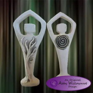 Two white stone figurines with elongated bodies and heart-shaped heads, one with flame details and one with spiral symbol