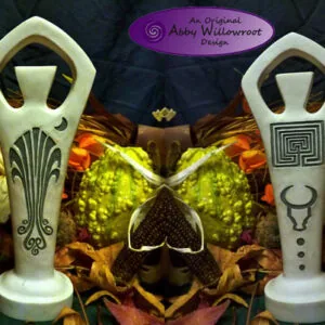 Two white ceramic decorative statues with art deco designs flanking a central ornament against gold and jewel-toned fabric backdrop