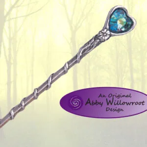 Wooden wand with spiral-wrapped handle and blue heart-shaped crystal at tip against misty forest background