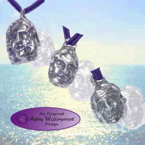 Three silver face pendants with purple ribbons hanging over a turquoise ocean backdrop
