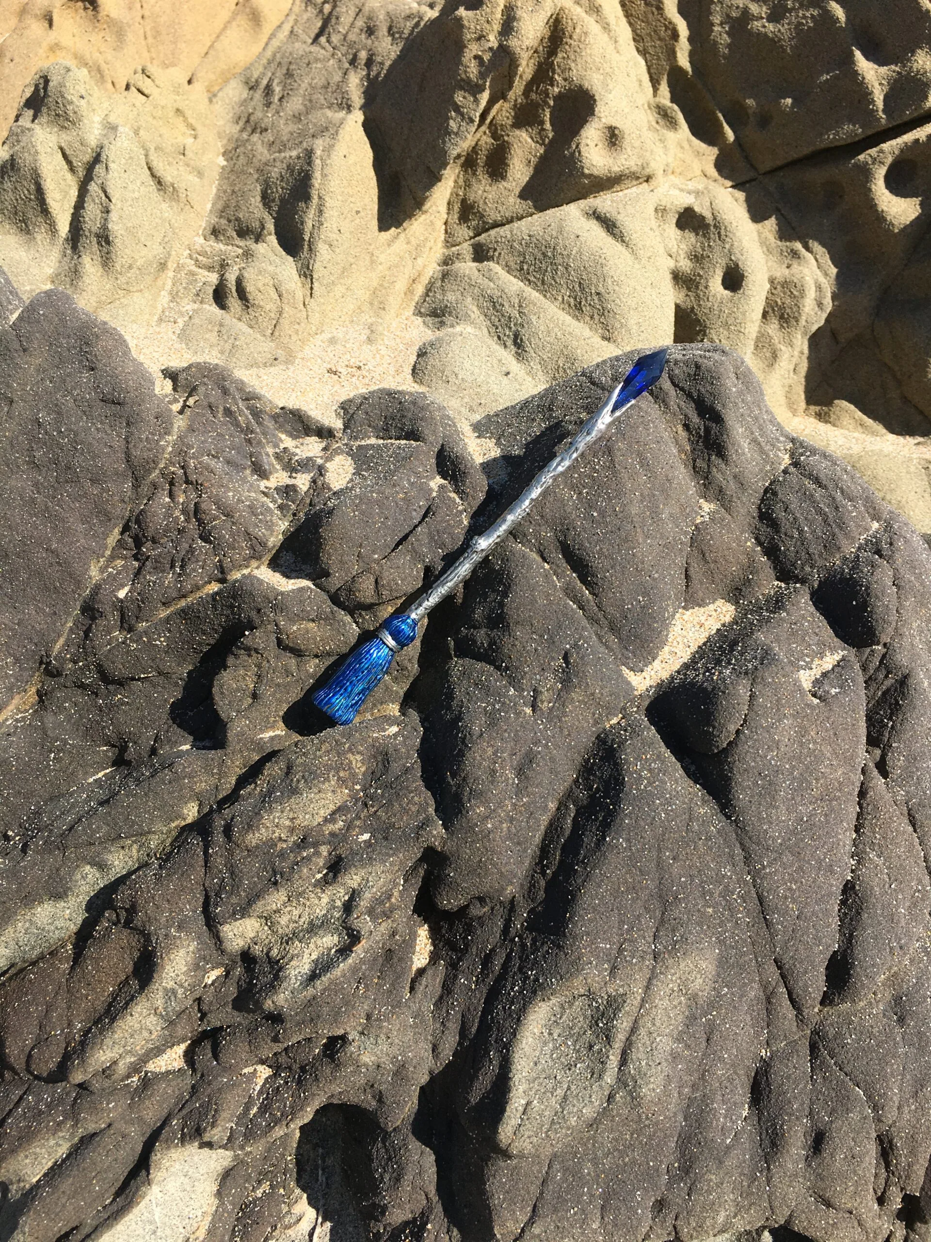 Blue paintbrush on rocky sand surface with textured geological formations