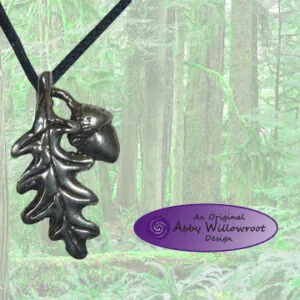 Pewter oak leaf and acorn pendant hanging from black cord against forest background