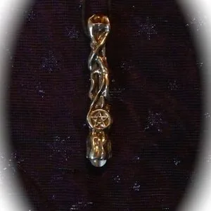 Gold twisted wand pendant with pentagram symbol and clear crystal drop on dark sparkly fabric