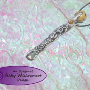 Pewter wand pendant with amber beads on black cord against patterned fabric background