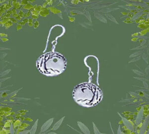 Pair of sterling silver earrings with circular pendants featuring tree branch design on green leafy background