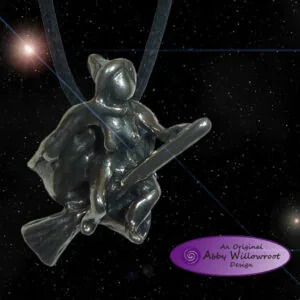 Clear glass pendant of a witch flying on a broomstick against starry black background