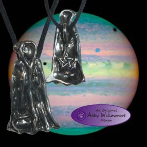 Two silver pewter witch pendants hanging from black cords against a colorful iridescent circular background