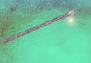 Ornate wooden wand with decorative metallic details on turquoise sparkling background